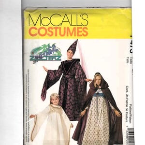 May include: A McCall's Costumes sewing pattern envelope featuring three individuals in fantasy-style outfits. One wears a purple patterned robe and pointed hat, another a white dress with gold trim, and the third a brown hooded cloak over a floral dress.