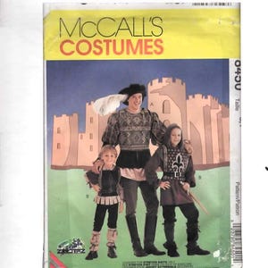 May include: A McCall's Costumes sewing pattern envelope featuring an illustration of three individuals wearing medieval-style outfits with tunics, leggings, and boots. The background shows a castle silhouette, and the text reads McCall's Costumes.