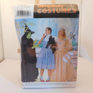 May include: Simplicity Costumes pattern for The Wizard of Oz costumes. The pattern shows three women dressed as Dorothy, Glinda the Good Witch, and the Wicked Witch of the West.