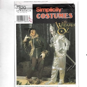May include: A Simplicity Costumes sewing pattern envelope for The Wizard of Oz, featuring illustrations of a scarecrow in a dark green tunic with straw accents and a tin man in a metallic silver suit holding an axe, labeled with pattern number 7820.