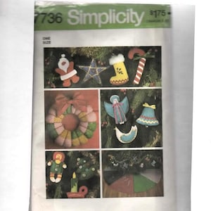 May include: A Simplicity 7736 sewing pattern envelope featuring illustrations of various Christmas ornaments including a Santa, star, stocking, candy cane, wreath, angel, bell, bird, doll, tree, candle, and a tree skirt, all displayed on a white background.