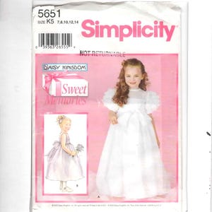 May include: Simplicity sewing pattern for a girl's dress. The pattern features a young girl in a white dress with a bow. The text "Sweet Memories" and "Daisy Kingdom" are also visible. Size K5, sizes 7, 8, 10, 12, and 14.