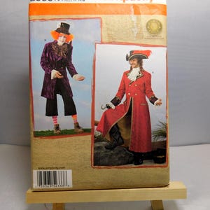 May include: Simplicity sewing pattern number 2333 AA for sizes XS-M. The pattern includes instructions and templates for making two costumes: a purple velvet jacket with a white ruffle collar and black pants, and a red jacket with gold trim and a white ruffle collar. The pattern is for adults.