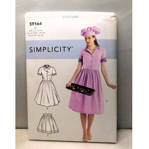 May include: Simplicity costume pattern S9164. The package features a woman in a lavender chef costume, holding a tray. The pattern includes illustrations of the dress and skirt. The text on the package includes "COSTUME" and "SIMPLICITY".
