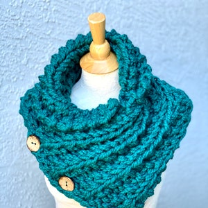 May include: Teal blue knitted cowl neck scarf with three wooden buttons.