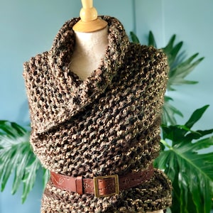 Puede incluir: Un cuello de punto marr&oacute;n y verde con un cintur&oacute;n de cuero marr&oacute;n. El cuello est&aacute; drapeado sobre un maniqu&iacute; blanco.