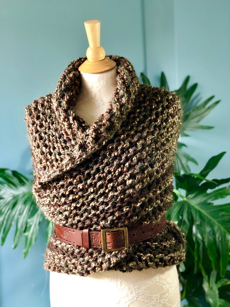 Puede incluir: Un cuello de punto marr&oacute;n y verde con un cintur&oacute;n de cuero marr&oacute;n. El cuello est&aacute; drapeado sobre un maniqu&iacute; blanco.