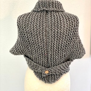 Pu&ograve; includere: Cappotto di maglia grigio con collo alto e chiusura a bottone. Il cappotto &egrave; realizzato con un filato spesso e ha una vestibilit&agrave; comoda.