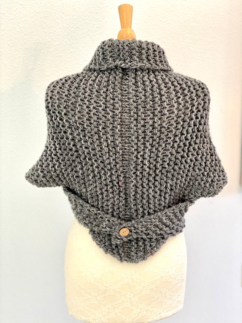 Pu&ograve; includere: Cappotto di maglia grigio con collo alto e chiusura a bottone. Il cappotto &egrave; realizzato con un filato spesso e ha una vestibilit&agrave; comoda.