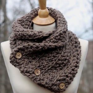 Puede incluir: Una bufanda de punto infinito de color marrón con cierres de botones de madera.