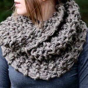 May include: A brown and gray knitted infinity scarf with a chunky texture.