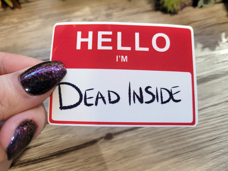 May include: A red and white name tag with the text "HELLO I'M DEAD INSIDE" written in black marker.