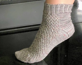May include: A pair of grey ankle socks with a lacy pattern. The socks are knitted and have a subtle sheen.