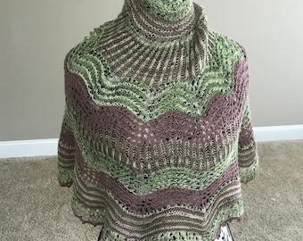 May include: A green and brown knitted shawl with a lacy pattern, displayed on a black mannequin.