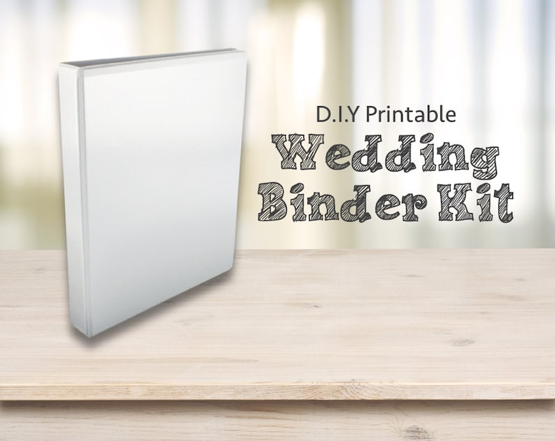 Op de afbeelding: Een witte map op een houten tafel met de tekst "D.I.Y Printable Wedding Binder Kit" in zwart.