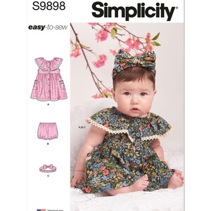 May include: Simplicity sewing pattern S9898 easy-to-sew for a baby dress, bloomers, and headband. The pattern shows a baby wearing a floral print dress with a lace trim and a matching headband.