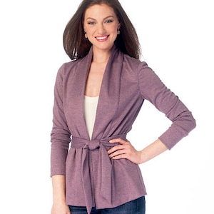 May include: A mauve cardigan with a long, draped collar and a self-tie belt. The cardigan is made of a soft, knit fabric.