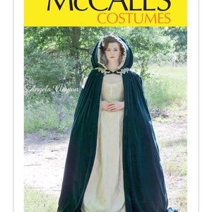 May include: A green velvet hooded cape with a white lace trim. The cape is worn over a white dress with a green sash. The model is standing in a wooded area. McCall's Costumes M7886.