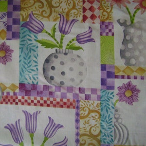 May include: A white fabric with a patchwork design featuring purple, green, and yellow floral motifs. The fabric has a checkered pattern and a repeating design of a vase with flowers.