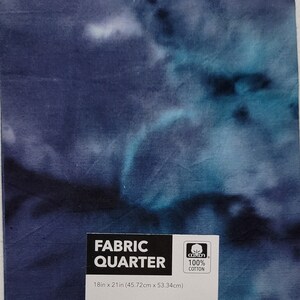 May include: A fabric quarter with a tie-dye design in shades of blue and white. The fabric measures 18 inches by 21 inches and is made of 100% cotton. The fabric is a dark blue with lighter blue and white swirls.
