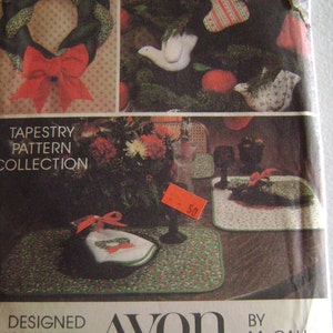 May include: A vintage Avon tapestry pattern collection featuring a Christmas wreath, stocking, and doves. The pattern includes placemats and napkins with a green and red floral design. The package is labeled "Designed Exclusively for Avon by McCall Patterns".