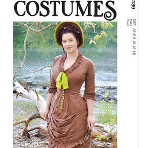 May include: McCall's Costumes pattern featuring a woman in a brown vintage dress with a green bow and hat. The dress has a ruffled neckline and sleeves, with a fitted bodice and a draped skirt. The pattern includes size A5 (6-8-10-12-14).