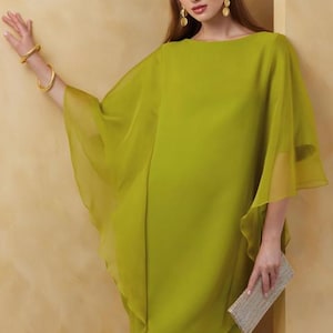 May include: A lime green dress with a flowing, sheer overlay. The dress has a simple, round neckline and a short, fitted silhouette.