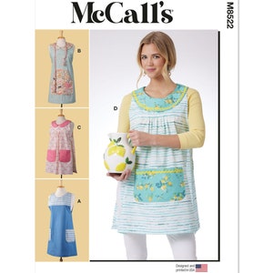 May include: McCall's M8522 sewing pattern featuring aprons. The image shows a woman wearing an apron with a blue and white striped design, a yellow collar, and a pocket with a lemon pattern. Other apron designs are also shown.