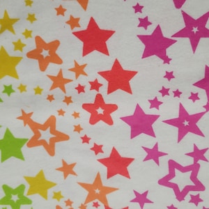 May include: White fabric with a repeating pattern of colorful stars in shades of yellow, green, orange, red, pink, and purple. The stars vary in size and are arranged in a scattered, whimsical design.