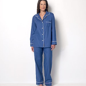 May include: A blue pajama set with white piping. The top has a button-up front and a chest pocket. The pants have a straight leg.