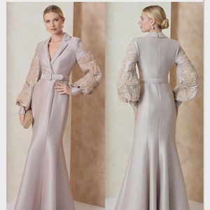 May include: Vogue Patterns V2153 Badgley Mischka sewing pattern for a floor-length, light mauve dress with a belted waist, notched lapels, and long, voluminous sheer sleeves featuring intricate sequin and bead embellishments on the fabric.