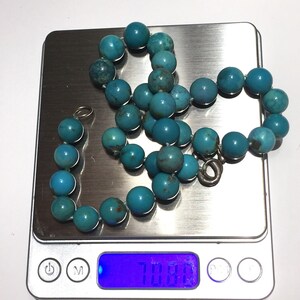 Puede incluir: Un collar de cuentas turquesa con cierre de plata, que pesa 70,8 gramos, en una b&aacute;scula digital.