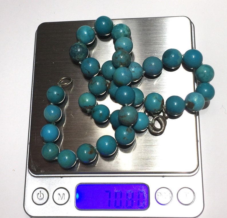 Puede incluir: Un collar de cuentas turquesa con cierre de plata, que pesa 70,8 gramos, en una b&aacute;scula digital.