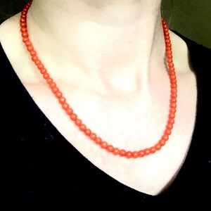 Puede incluir: Un collar hecho de peque&ntilde;as cuentas redondas de coral naranja.