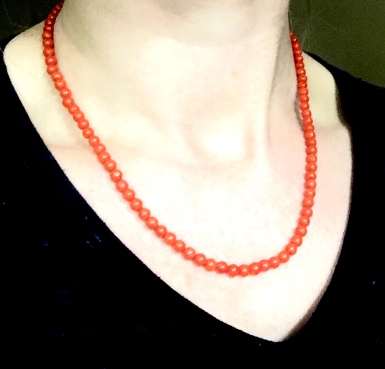 Puede incluir: Un collar hecho de peque&ntilde;as cuentas redondas de coral naranja.