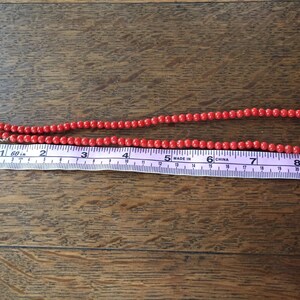 Puede incluir: Un collar de cuentas de coral rojo con un cierre de plata, que mide 20 cm de largo.