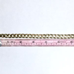 May include: A gold chain bracelet with a heart-shaped charm encrusted with red rhinestones. The bracelet measures 7 inches long.