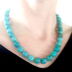 Puede incluir: Un collar de cuentas turquesa con cuentas redondas. El collar lo lleva una persona de tez clara.
