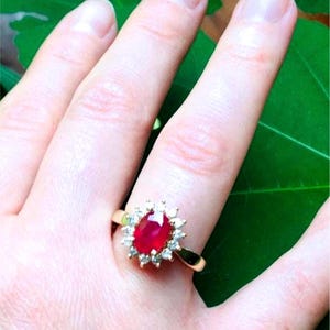 May include: A gold ring with a large oval ruby surrounded by smaller diamonds.