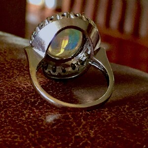 May include: A silver ring with a large oval opal gemstone surrounded by a halo of smaller diamonds.