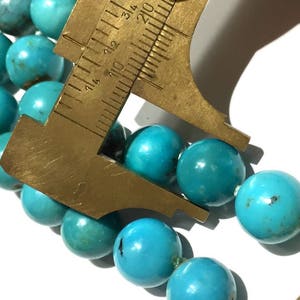 Puede incluir: Un collar de cuentas de color azul turquesa con una regla que mide las cuentas a aproximadamente 2,5 cm de di&aacute;metro.