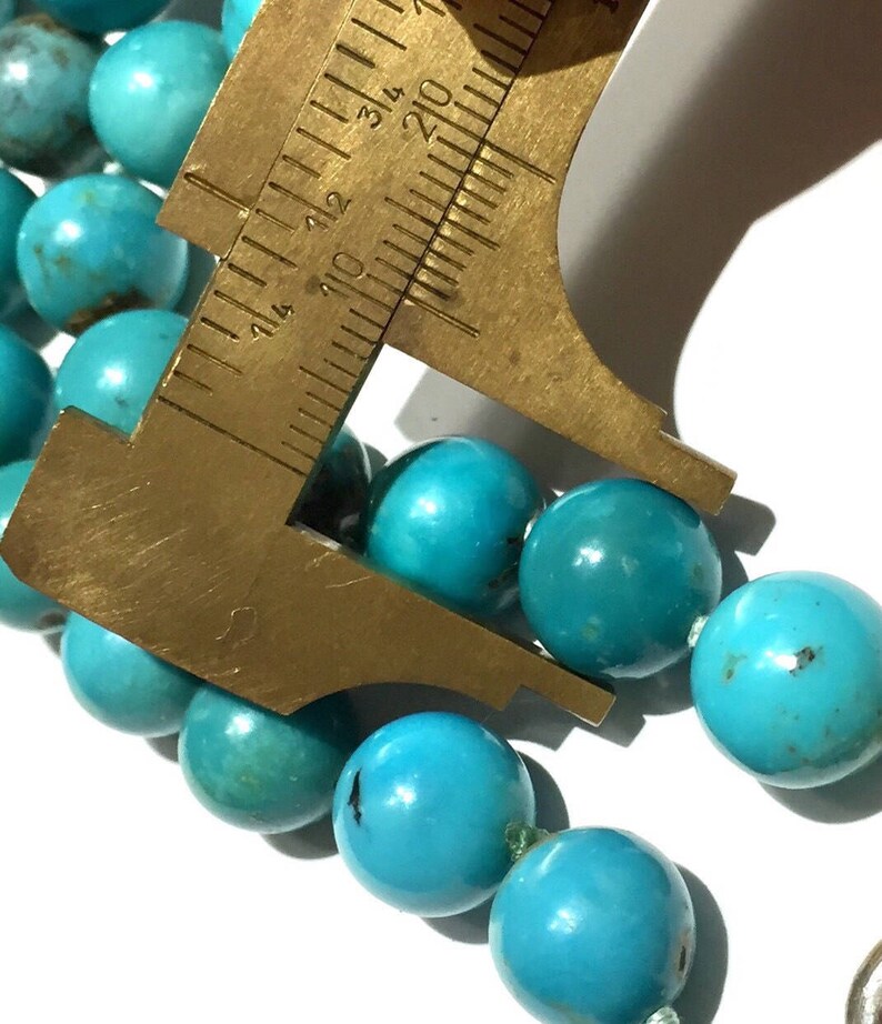 Puede incluir: Un collar de cuentas de color azul turquesa con una regla que mide las cuentas a aproximadamente 2,5 cm de di&aacute;metro.