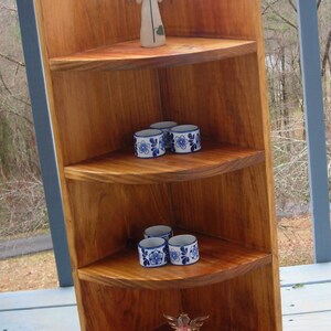 Peut inclure: Une &eacute;tag&egrave;re d'angle en bois avec trois &eacute;tag&egrave;res. L'&eacute;tag&egrave;re sup&eacute;rieure pr&eacute;sente une petite figurine d'ange blanche. L'&eacute;tag&egrave;re du milieu a quatre tasses en c&eacute;ramique bleu et blanc. L'&eacute;tag&egrave;re inf&eacute;rieure a une figurine d'ange rose et blanche.