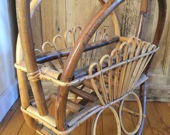 May include: A vintage, handcrafted rattan magazine rack. The rack features a curved handle, a rectangular basket, and decorative circular elements. The natural brown and tan tones of the rattan create a warm, inviting aesthetic. The rack is designed to hold magazines or other reading materials.