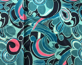 May include: Close-up of a fabric with a repeating abstract floral pattern. The design features swirling shapes in teal, navy, and pink. The fabric has a textured appearance, with a subtle grid-like pattern visible throughout the design.