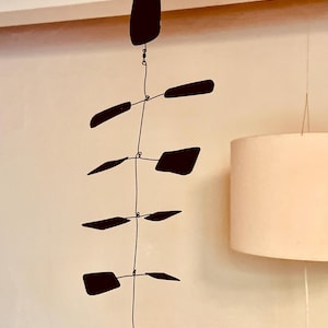 Puede incluir: Escultura móvil moderna de metal negro, suspendida de un alambre. Presenta una pieza superior en forma de lágrima y varias formas rectangulares e inclinadas colgando debajo. La escultura está suspendida del techo.