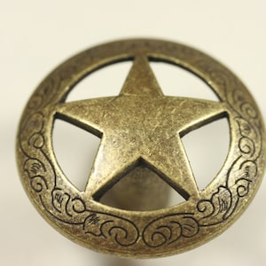May include: A gold-toned metal knob with a five-pointed star cut-out design and a decorative border.