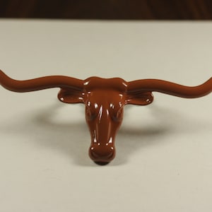 May include: A brown ceramic bull head with large horns. The bull head is a decorative object.