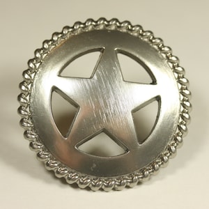 May include: A silver-toned metal belt buckle with a five-pointed star design. The star is cut out and the buckle has a rope-like border.