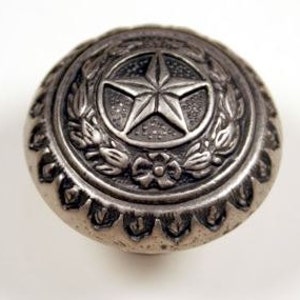 May include: Silver-toned metal cabinet knob with a raised design of a five-pointed star surrounded by a wreath of leaves and flowers.